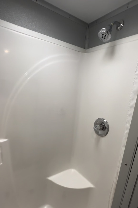 Modern white corner shower enclosure with fixtures.