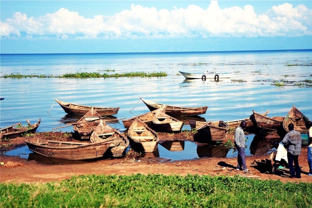 Wooden boats on lakeshore with people.