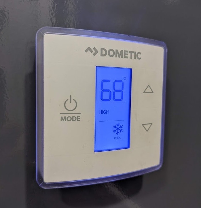 Dometic thermostat displaying 68 degrees on blue screen.