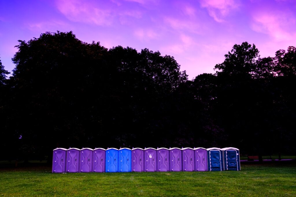 Row of portable toilets at dusk in park