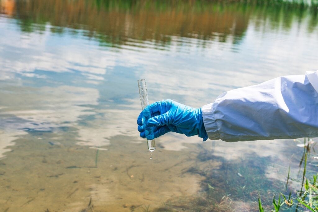 Scientist collecting water sample from lake.