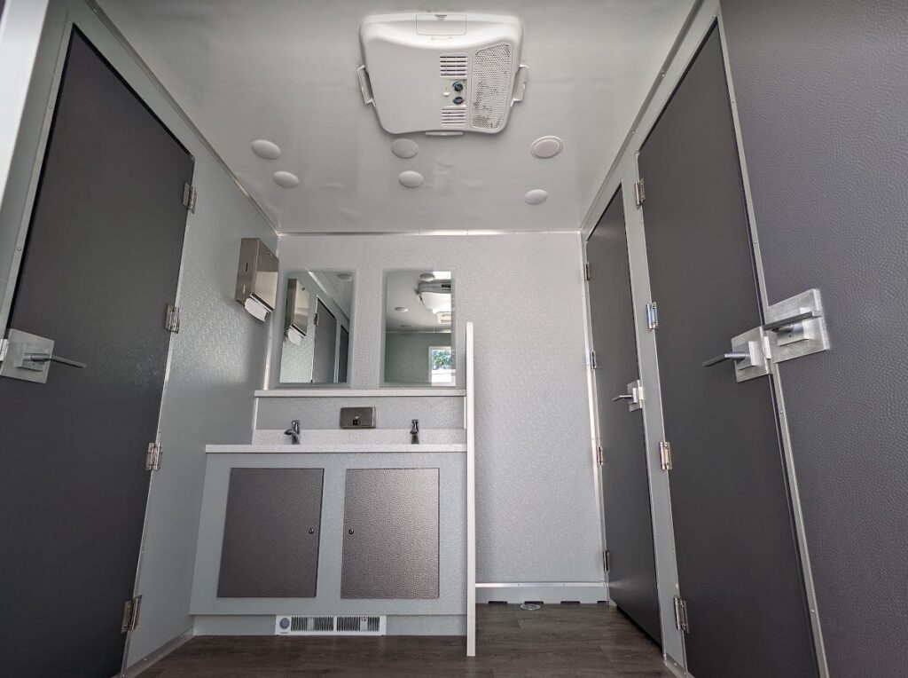 Interior of modern mobile restroom with sinks and stalls.