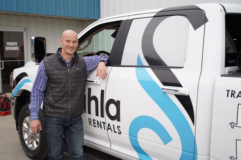 Man standing by branded rental van smiling.