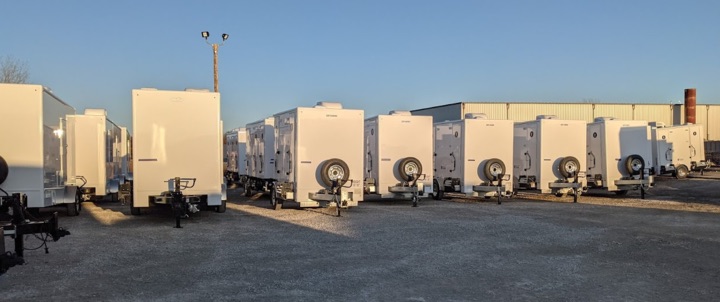 Row of white refrigerated trailers in storage lot.