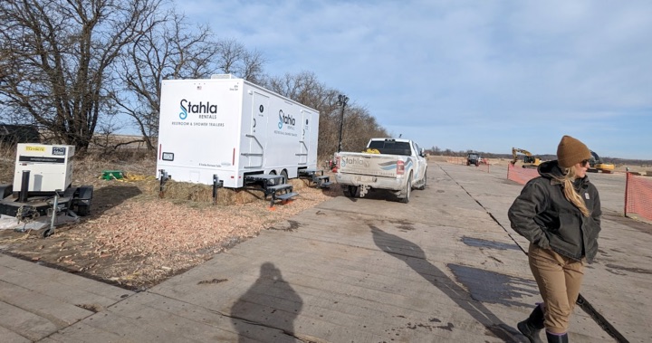 Construction site with portable restrooms and walking individual.