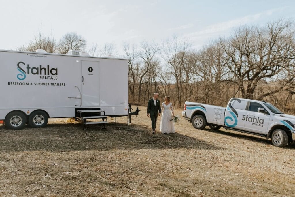 Bride and groom walking by rental trailer.