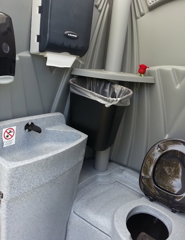 Interior of portable restroom with sink and waste bin.