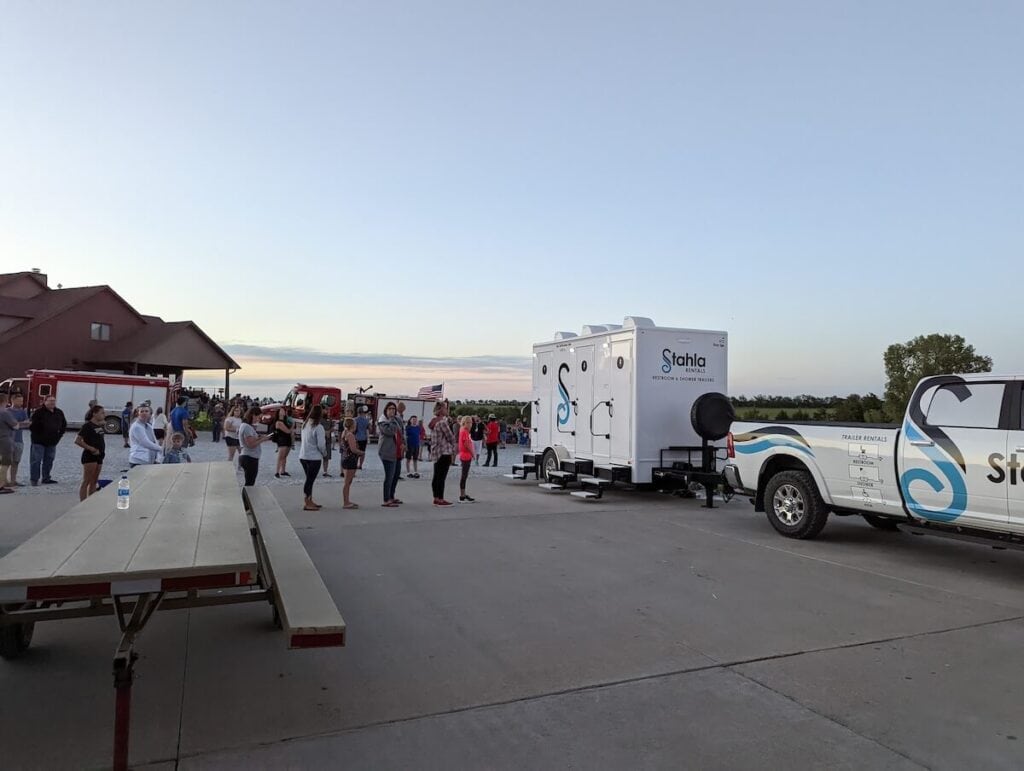 Crowd gathering near mobile trailer and truck at dusk.