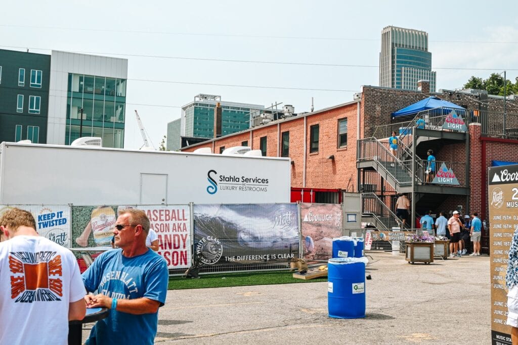 Outdoor event with luxury restroom trailer and attendees.