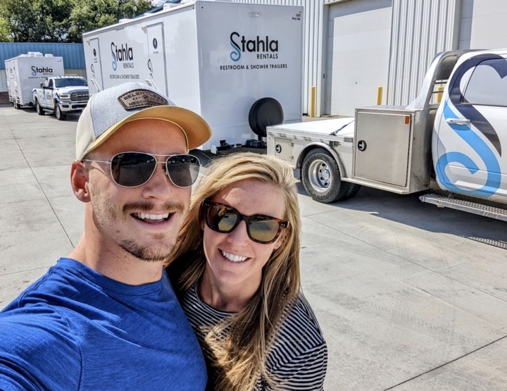 Couple smiling in front of rental trailers.