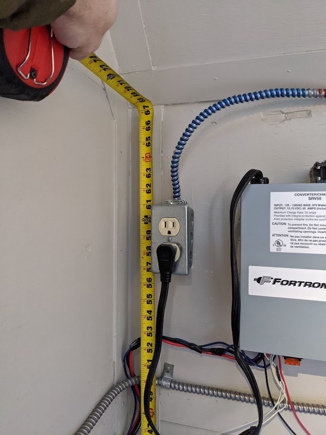 Measuring electrical outlet installation with tape measure.