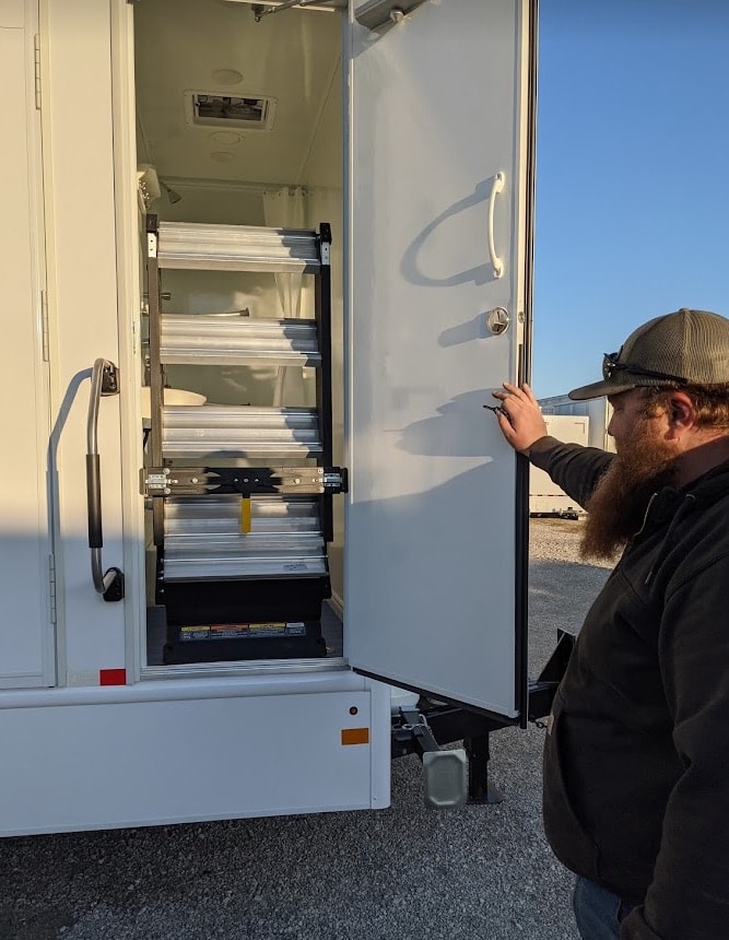 Man inspecting retractable RV steps outdoors.