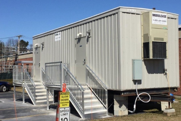 Portable office trailer with stairs and safety signs.