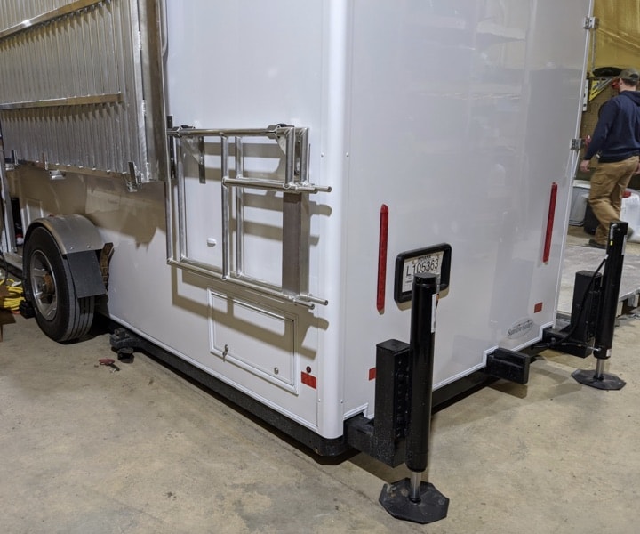White cargo trailer with rear stabilizing jacks down.