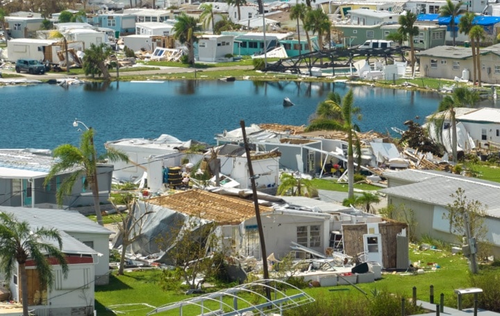 Devastated neighborhood after hurricane with damaged homes.