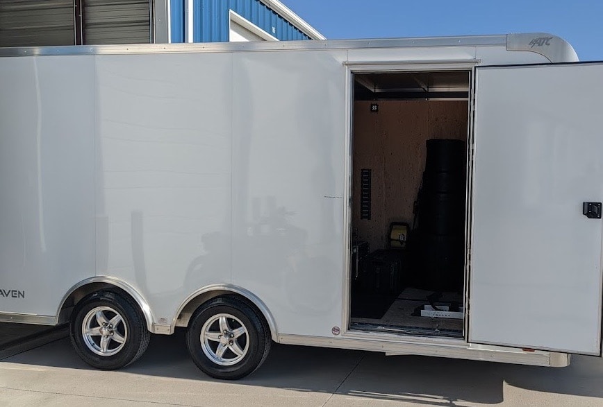Enclosed white cargo trailer with open door.