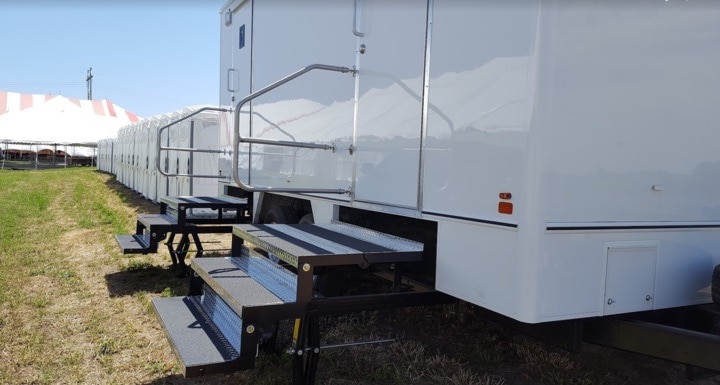 Mobile event trailers with steps and striped tent.