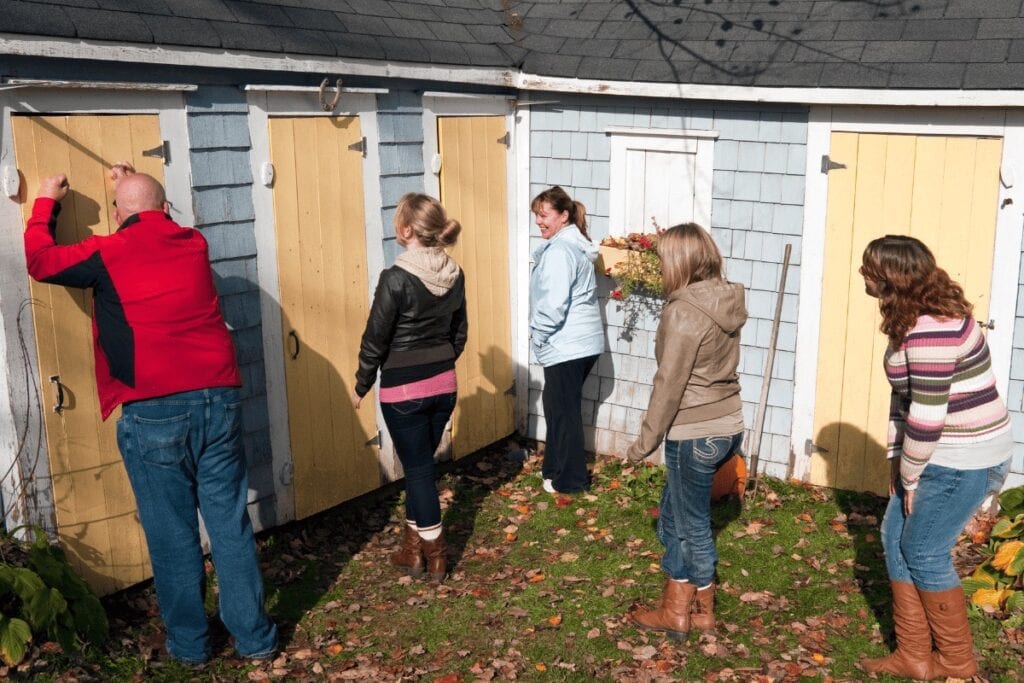 People painting and observing outdoor sheds.
