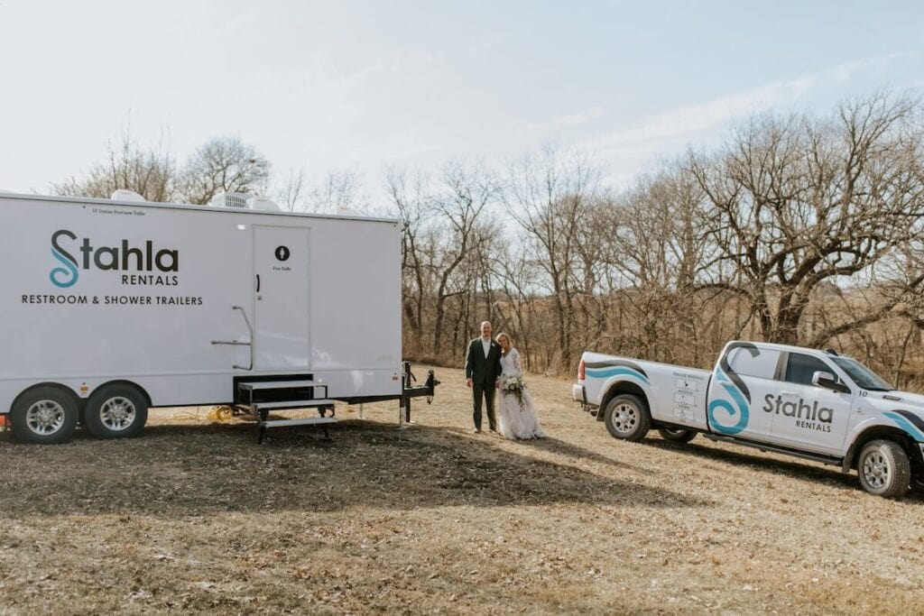 Couple by restroom trailer and pickup outdoors.