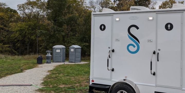Portable restrooms and trailer in outdoor setting.