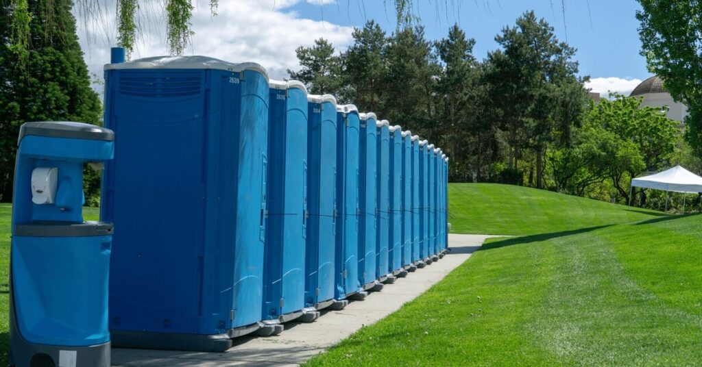 Image 1: Row of Event Porta Potties lined up in a park.