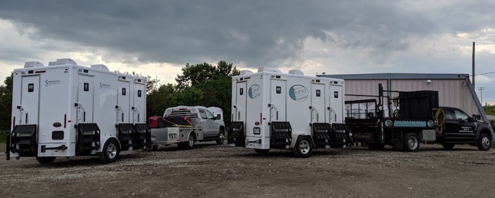 Mobile restrooms lined up in an outdoor lot.
