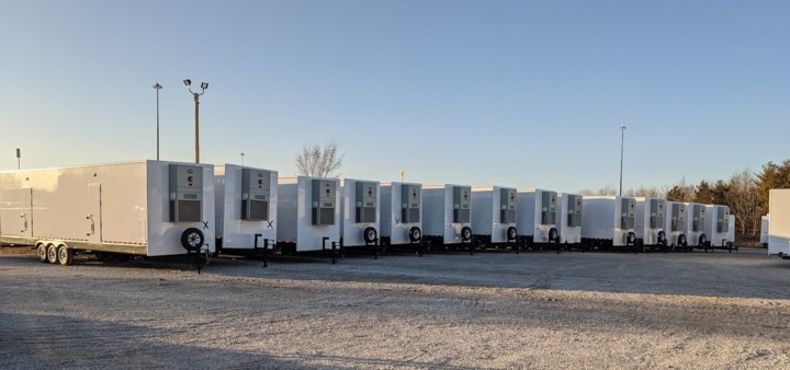 Row of white mobile trailers in lot.