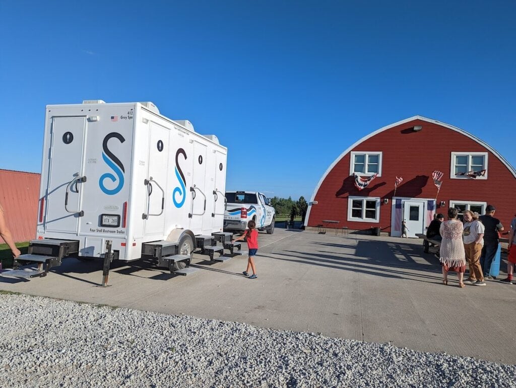 Mobile restroom trailers near red barn event venue.