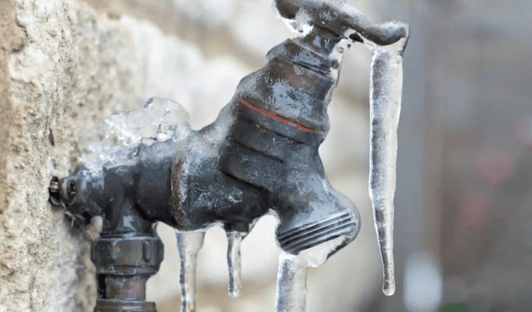 Frozen outdoor faucet with icicles hanging.