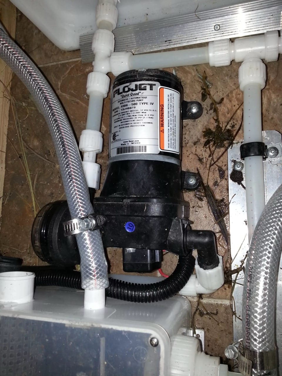 Flojet water pump installation with pipes and wiring.