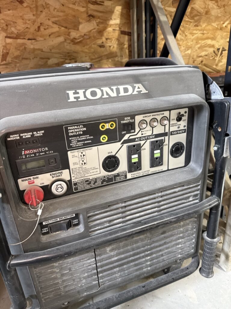 A Honda portable generator with control panel, outlets, switches, and indicator lights—ideal for powering restroom trailers—set against a wooden wall background.