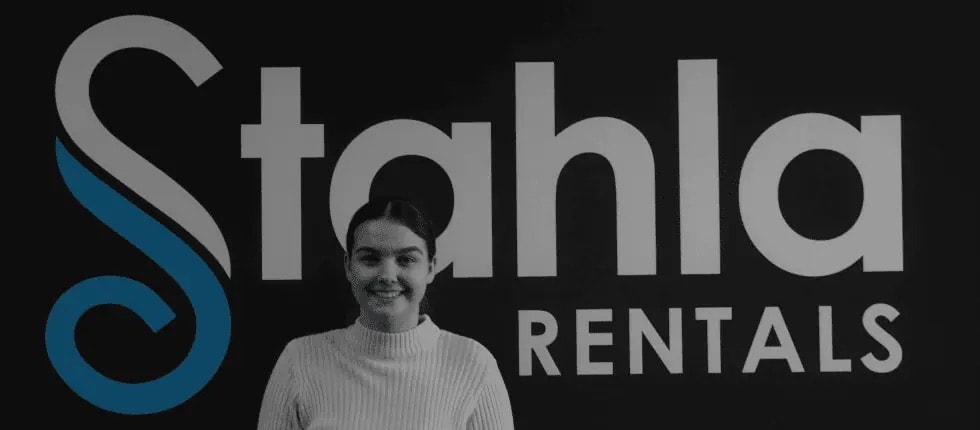 Woman smiling in front of Stahla Rentals logo.