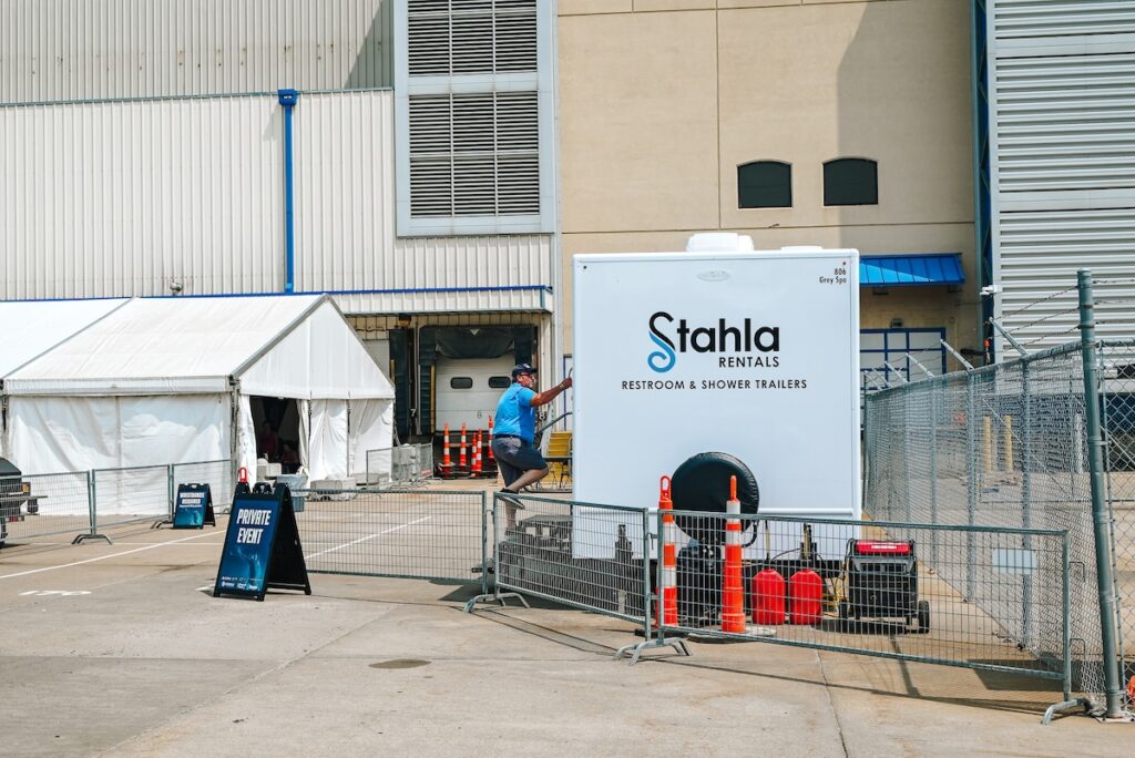 Man near mobile restroom and shower rental unit.
