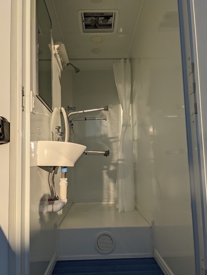 Compact bathroom with sink and shower curtain.