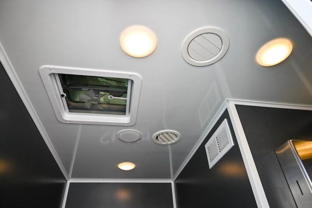 a bathroom ceiling features several lights, ventilation grates, and an open skylight designed by stahla services.