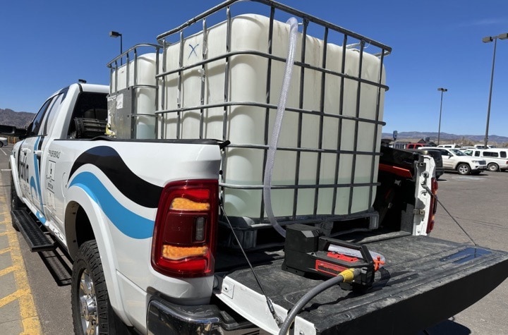 Pickup truck carrying large industrial water tanks.