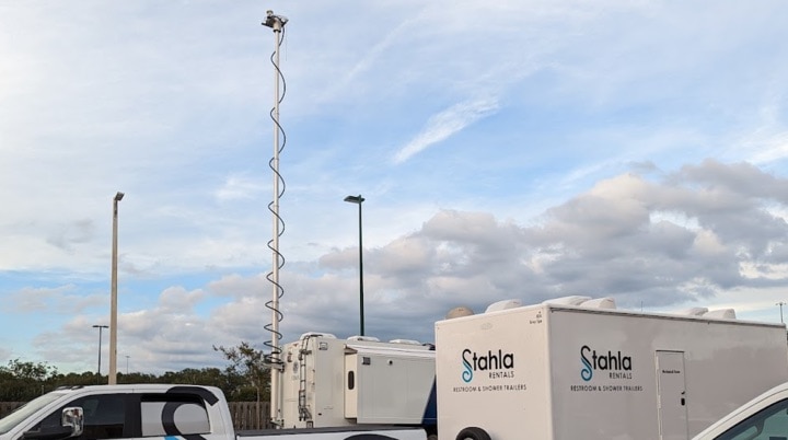 Mobile surveillance tower and rental trailers in lot.