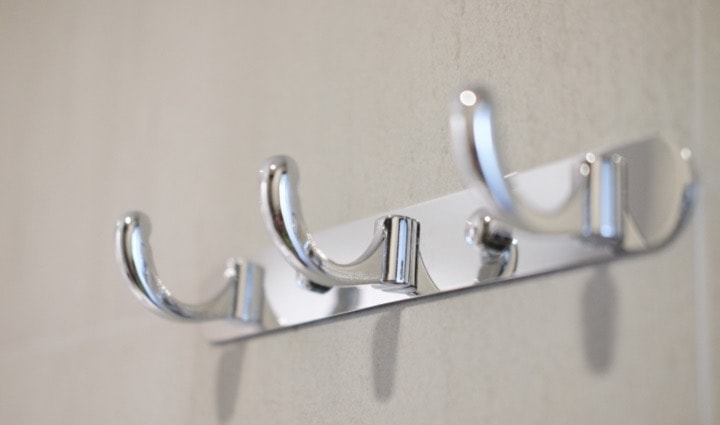 Chrome wall-mounted coat hooks on light background.