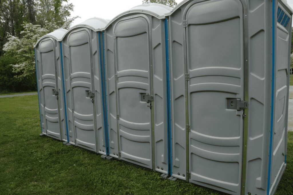 Row of portable toilets in outdoor setting.